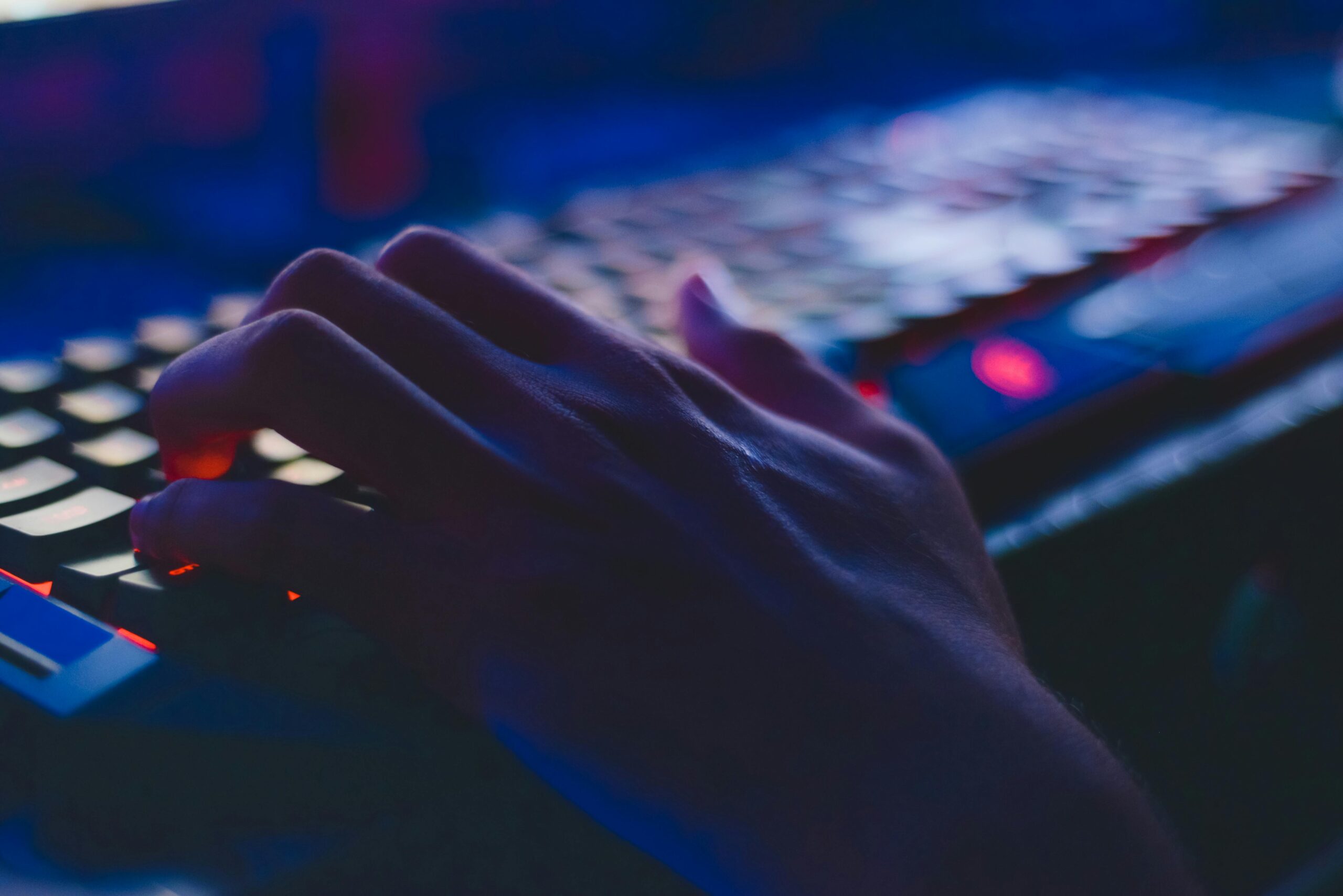 A hand typing on a glowing keyboard in dim lighting, perfect for tech themes.